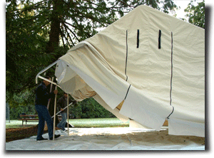 Two people setting up a canvas wall tent.